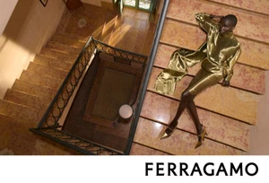 Anok Yai reclining on a grand marble staircase wearing a glossy gold outfit for Salvatore Ferragamo Fall-Winter 2026 campaign