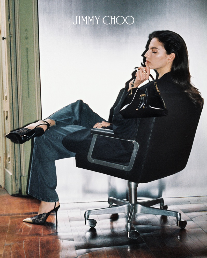 Model Africa Garcia seated in an office chair holding a black handbag for Jimmy Choo Fall 2026 Campaign