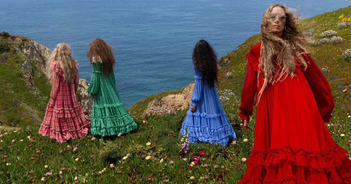 Four models in long colorful ruffled dresses standing on a coastal cliff above the ocean for Chloe Fall-Winter 2026 campaign.