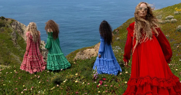 Four models in long colorful ruffled dresses standing on a coastal cliff above the ocean for Chloe Fall-Winter 2026 campaign.