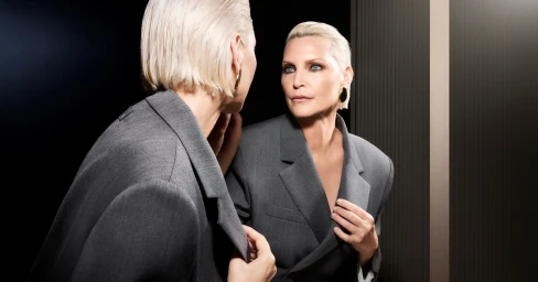 Nadja Auermann in a grey blazer looking into a mirror for the Ports 1961 Fall-Winter 2026 campaign photographed by Rankin.