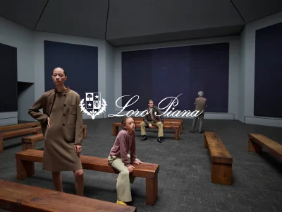 Models in brown apparel posing inside a gallery space with dark wall panels and wooden benches for Loro Piana