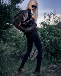 Model with wet blonde hair and large sunglasses carrying a patterned Gucci tote bag in an outdoor setting