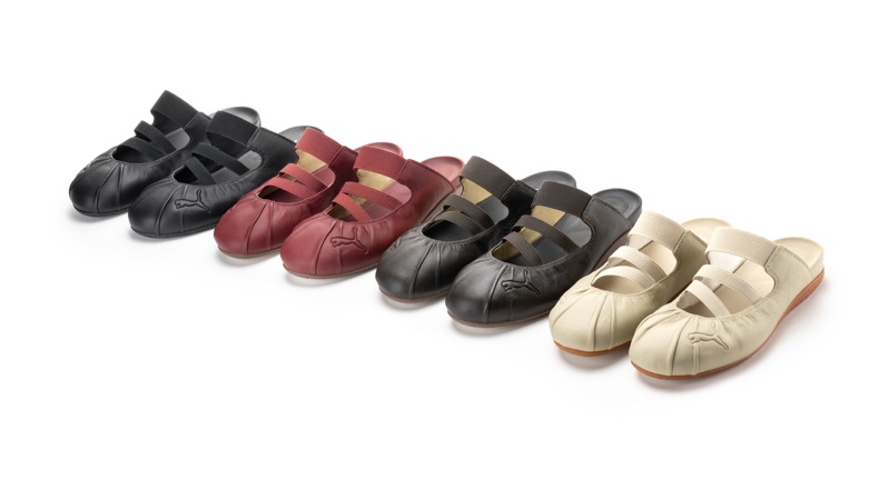 Four pairs of Puma Speedcat Mule footwear in black, burgundy, grey, and cream arranged diagonally on a white seamless background.