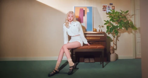 ROSÉ posing seated on a piano bench in a white Puma tracksuit and black mules for the Speedcat Mule campaign.