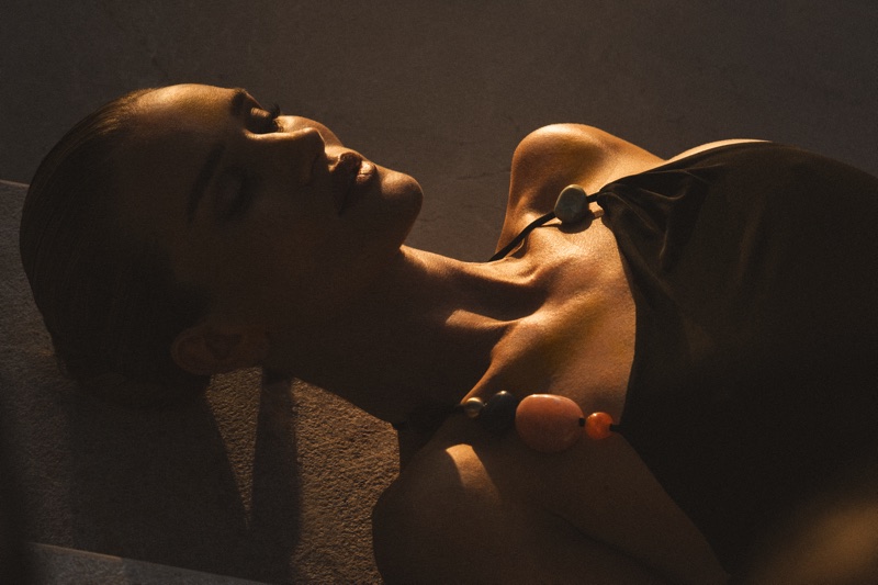 Rosie Huntington-Whiteley wearing a dark top with statement beads in warm sunlight for FWRD Summer 2026