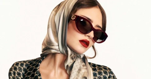 Model Leni Klum wearing burgundy sunglasses, printed headscarf, and patterned top against white background for Guess Forever Guess campaign