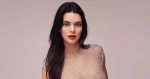 Kendall Jenner wearing a sheer silver mesh top against a neutral studio background for Tory Burch Sublime campaign