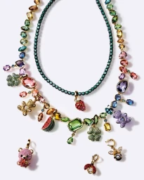 Colorful Swarovski crystal charm necklaces and playful charms displayed against a clean white seamless studio background.