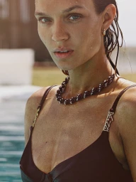 Close-up portrait of a model with wet hair wearing a black top and beaded necklace by Cameron Hammond for Kith Summer Escape