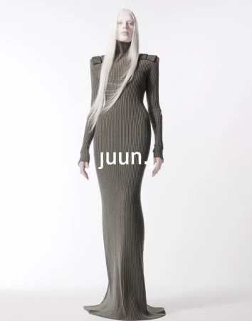 Fashion model with long silver hair poses in a full-length ribbed olive-green dress against a bright white backdrop in a studio setting.