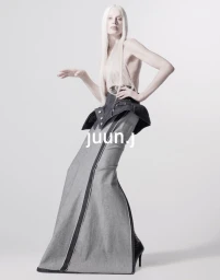 Kristen McMenamy poses in a sculptural Juun.J floor-length denim skirt against a white studio background.