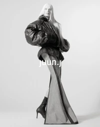 Kristen McMenamy posing in an oversized black jacket and flared trousers against a seamless studio background for Juun.J.