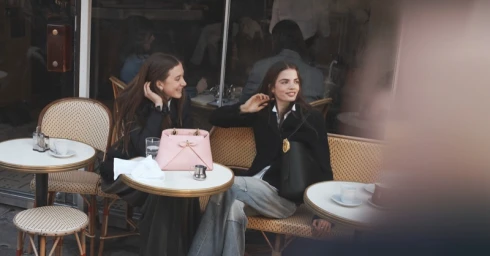 Two models seated at a café table on a sidewalk, captured by photographer David Sims for Dior.