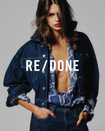 Kaia Gerber wearing a denim jacket and plaid shirt against a grey background