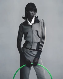 Model in grey tracksuit holding a bright green hoop against a neutral studio background for Adidas Originals by Avavav
