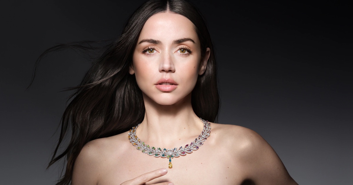 Ana de Armas wearing an intricate multi-gemstone collar necklace against a dark grey studio background.