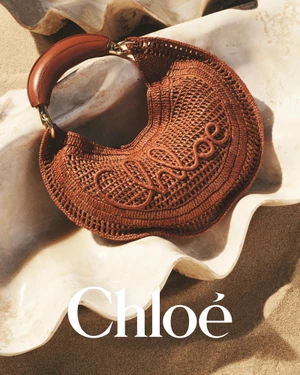 Brown crocheted handbag resting inside a large white seashell on sand for the Chloé a la Plage campaign.