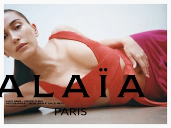 Hailey Bieber wearing an Alaia red dress while reclining on a studio floor