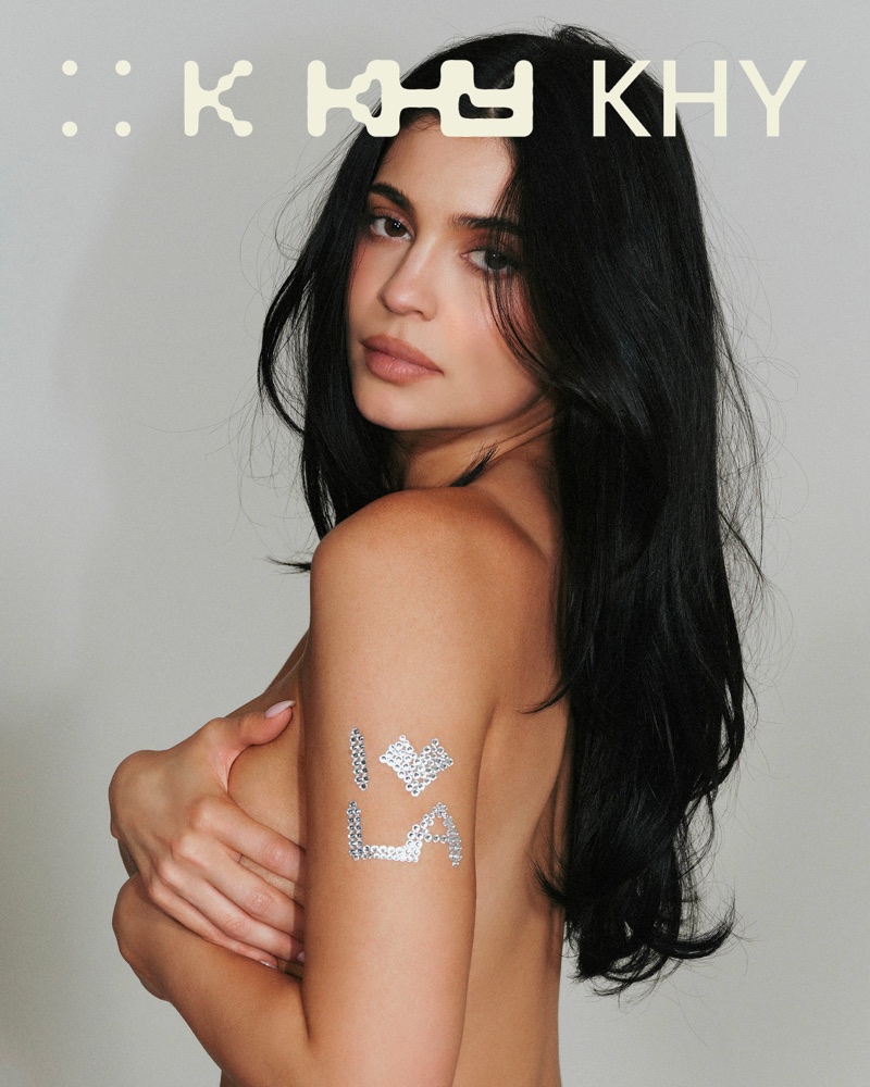 Kylie Jenner with long dark hair looking over her shoulder for Khy Born in LA campaign against a grey seamless background