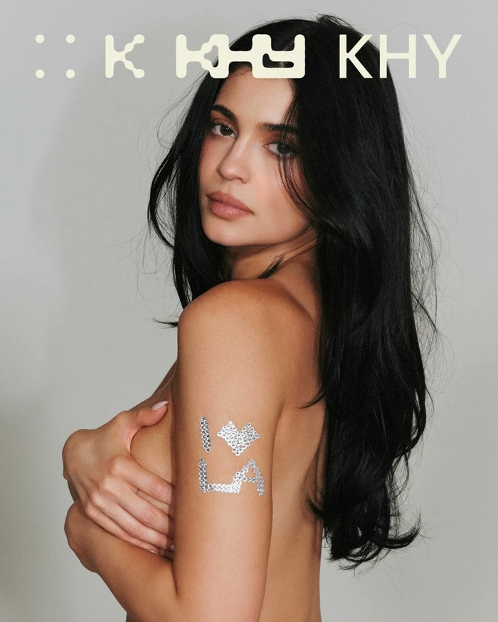 Kylie Jenner with long dark hair looking over her shoulder for Khy Born in LA campaign against a grey seamless background