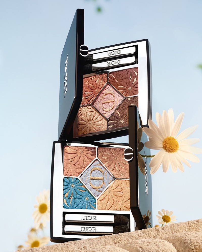 Two open Dior eyeshadow palettes featuring embossed floral patterns against a clear sky background with white daisies.