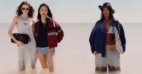 Three models standing in shallow water against a bright horizon, wearing Miu Miu spring summer apparel.