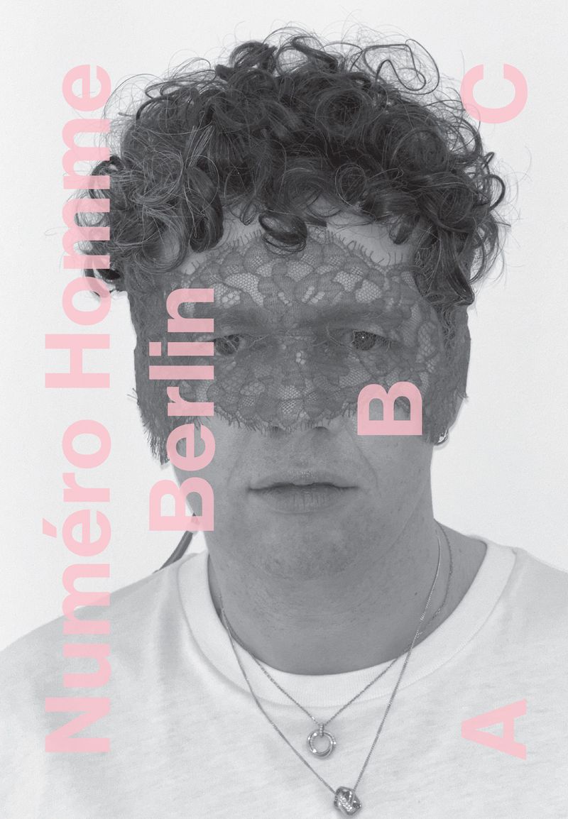 Portrait of a man wearing a lace mask with stylized magazine text, gray color grading, and a white background, showcasing fashion editorial style.