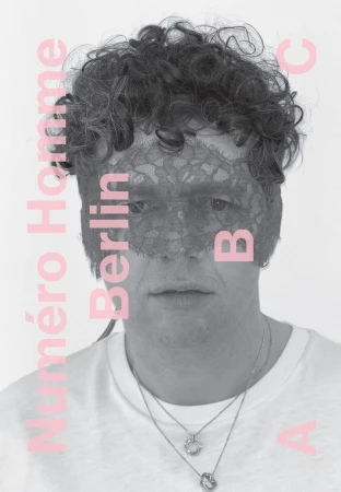 Portrait of a man wearing a lace mask with stylized magazine text, gray color grading, and a white background, showcasing fashion editorial style.