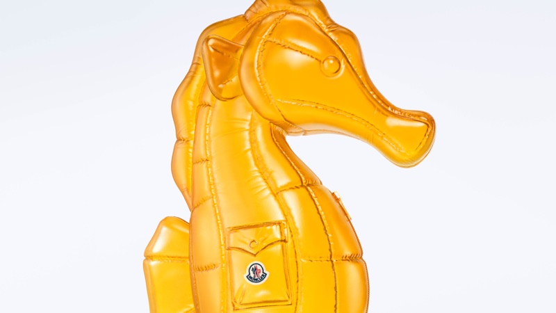 A glossy yellow quilted inflatable seahorse featuring a front pocket with a brand logo against a plain white backdrop.