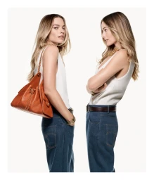 Margot Robbie wearing a white tank top and blue jeans with a brown handbag for the Chanel 25 Bag Campaign shot by Craig McDean.