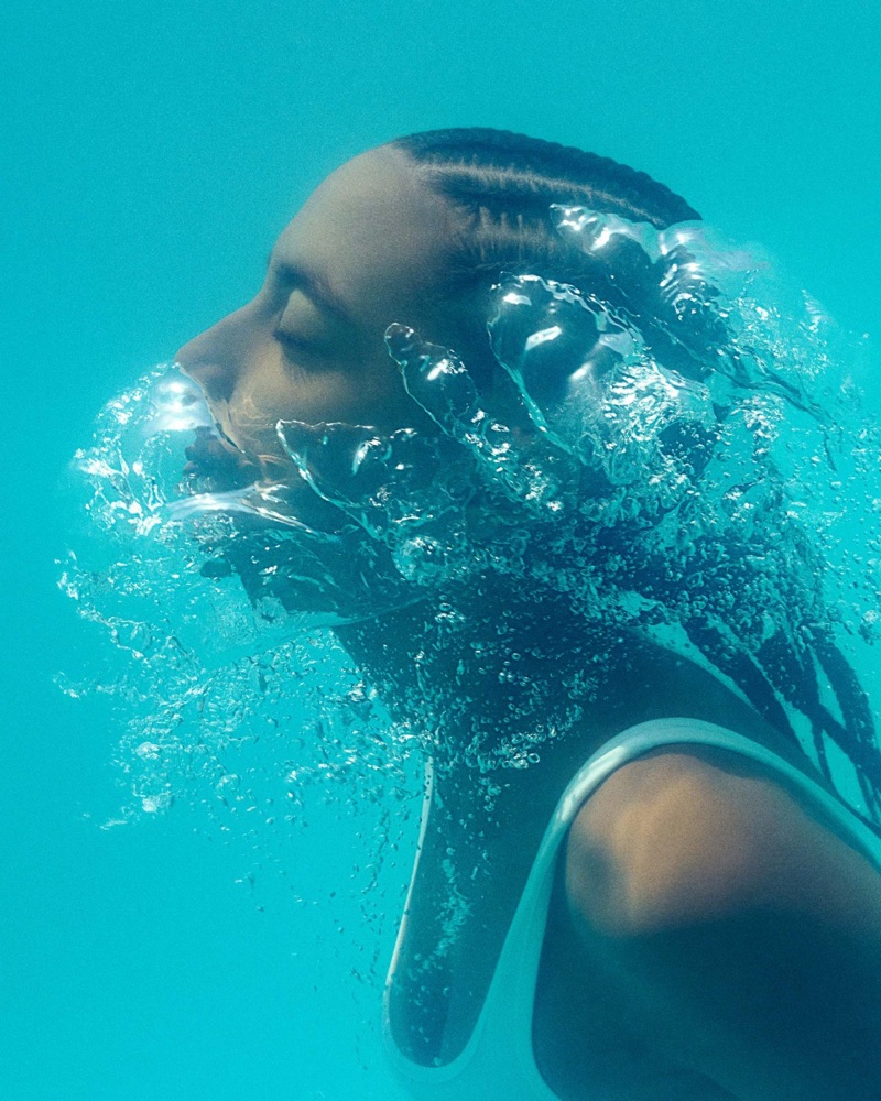 Close-up profile of Simone Ashley underwater with swirling air bubbles and bright turquoise water for Burberry High Summer 2026.