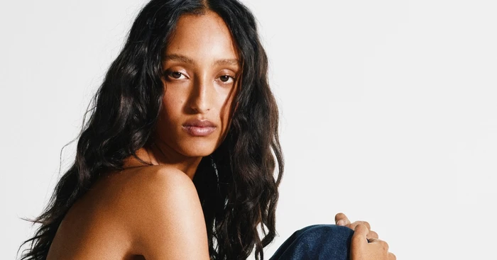 Portrait of Mona Tougaard with long dark hair wearing denim jeans against a white seamless background for Alaia
