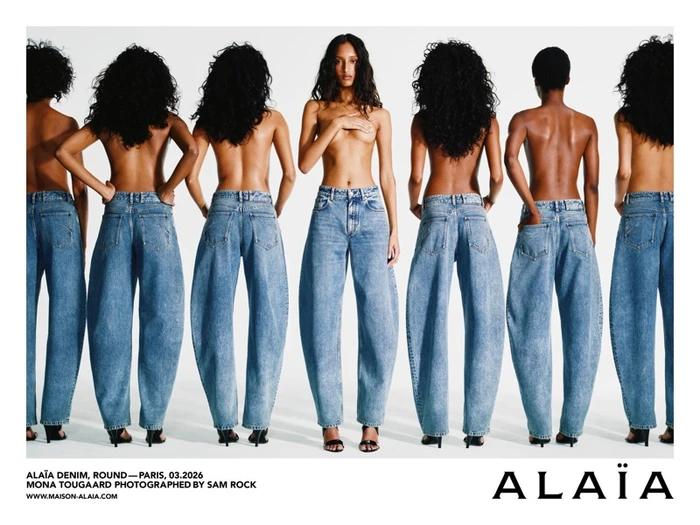 Model Mona Tougaard posing in blue denim jeans against a white seamless background for the Alaia campaign.