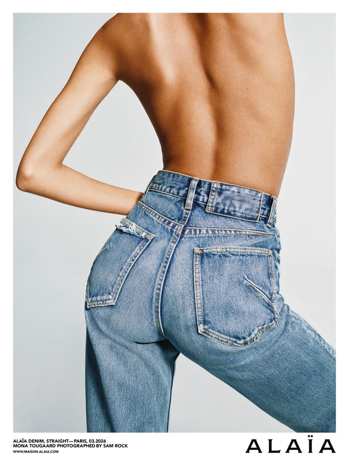 Close-up of Mona Tougaard wearing blue denim jeans with a bare back against a light grey studio background for Alaïa