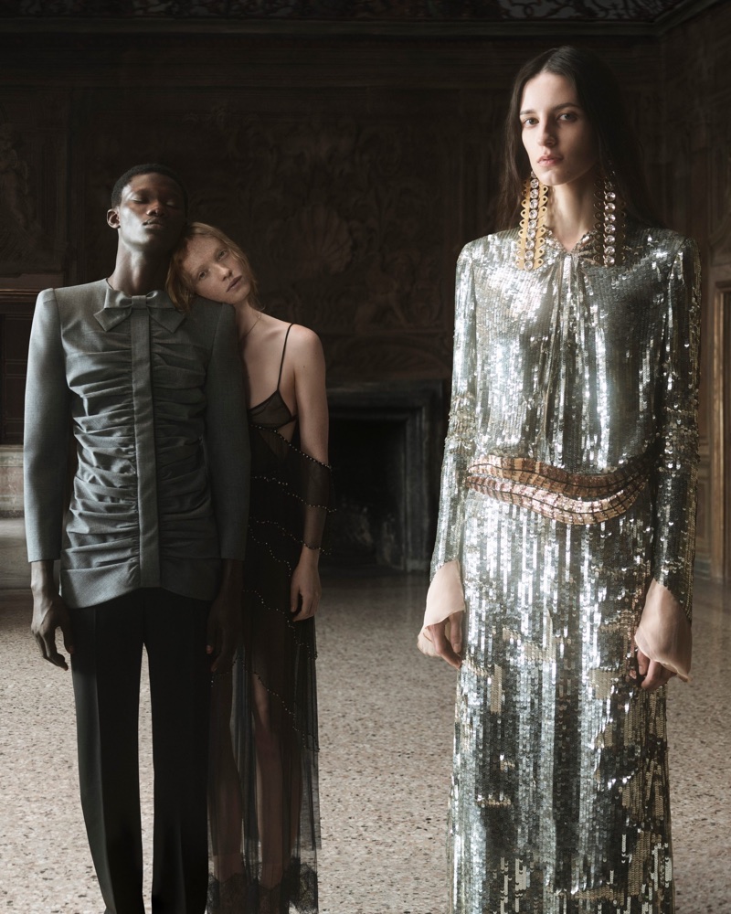 Models in high fashion clothing posing indoors in a dimly lit historic room for Valentino Fireflies