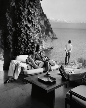 Black and white editorial image of models relaxing on a terrace overlooking the sea for Tod's Italian Stories campaign.