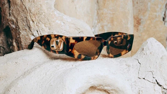 Valentino tortoiseshell sunglasses resting on textured beige rock formations