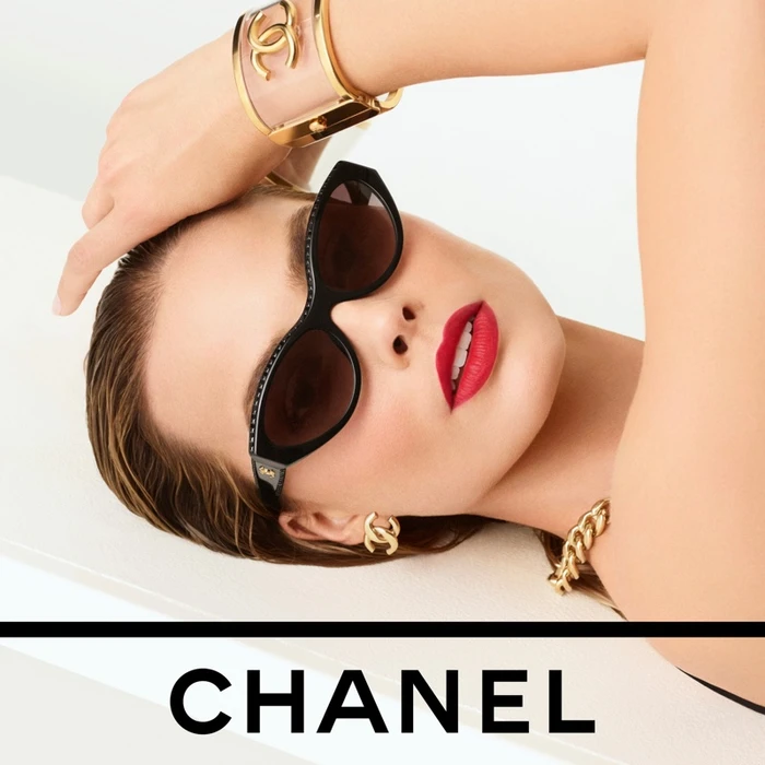 Margot Robbie wearing black sunglasses and gold jewellery with vibrant red lipstick for Chanel Rouge Allure Velvet.