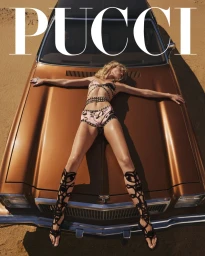Model lying flat on the hood of a bronze vintage car wearing patterned swimwear and tall black gladiator sandals