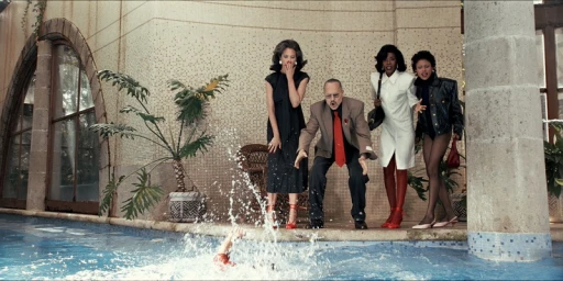 Four people standing shocked by a swimming pool watching someone splash in the water for Zara Vatísimo