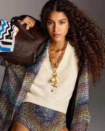 Model Luna Yohannan holding a brown leather bag and wearing a patterned coat with a gold chain necklace for Missoni Spring 2026