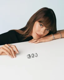 Woman resting chin on arms with rings displayed on white surface for Boucheron Quatre Is Getting Mini