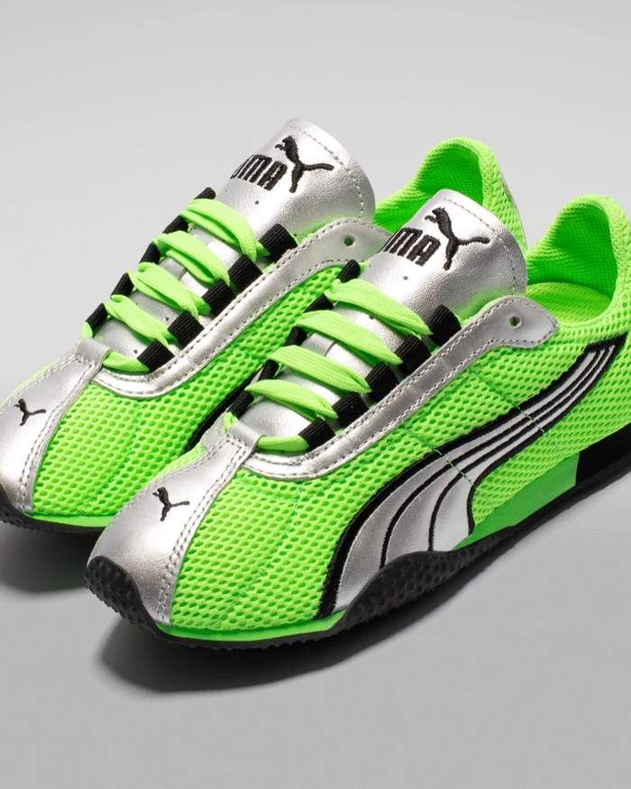 Bright green and silver Puma sneakers on a clean grey studio background