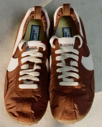 Top-down view of brown and white Nike Moon Shoe sneakers with laces and branded insoles resting on a plain surface.
