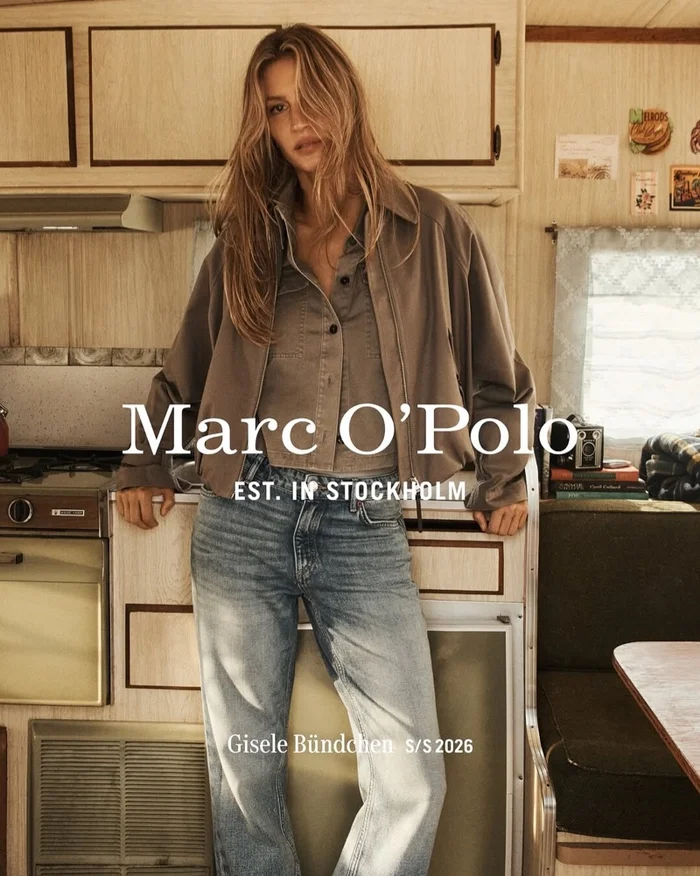 Gisele Bundchen wearing a brown jacket and blue jeans inside a campervan for Marc O'Polo Spring 2026 campaign.
