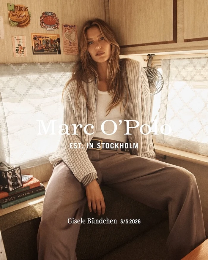 Gisele Bundchen wearing a cream knit cardigan and brown trousers inside a camper van for Marc OPolo Spring 2026 campaign