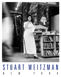 Ashley Graham standing outside a bookstore in a white dress and wedges for Stuart Weitzman
