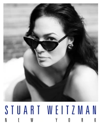 Ashley Graham wearing cat-eye sunglasses and dark top in a black and white campaign portrait for Stuart Weitzman