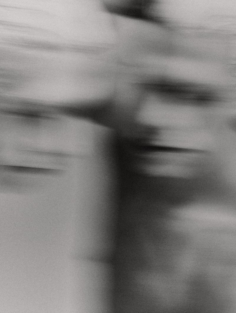Abstract, monochromatic image with blurred figure, horizontal lines and movement; an adult torso is only partially visible with high contrast.